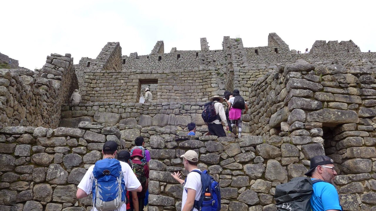 Visitors in layers, hats and daypacks exploring Machu Picchu