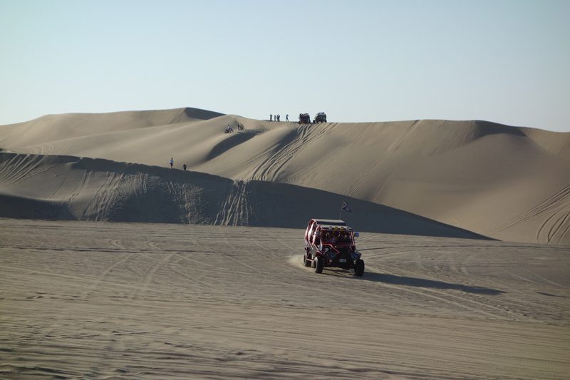 A dune buggy driving across the sand dunes outside the Huacachina oasis