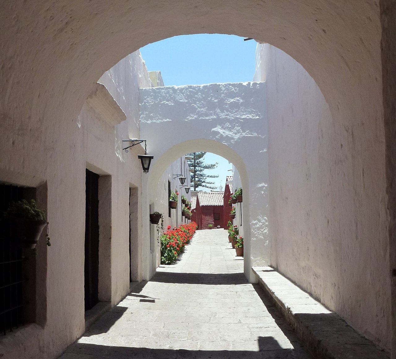 A whitewashed arched lane lined with pots of red geraniums inside the Santa Catalina Monastery in Arequipa