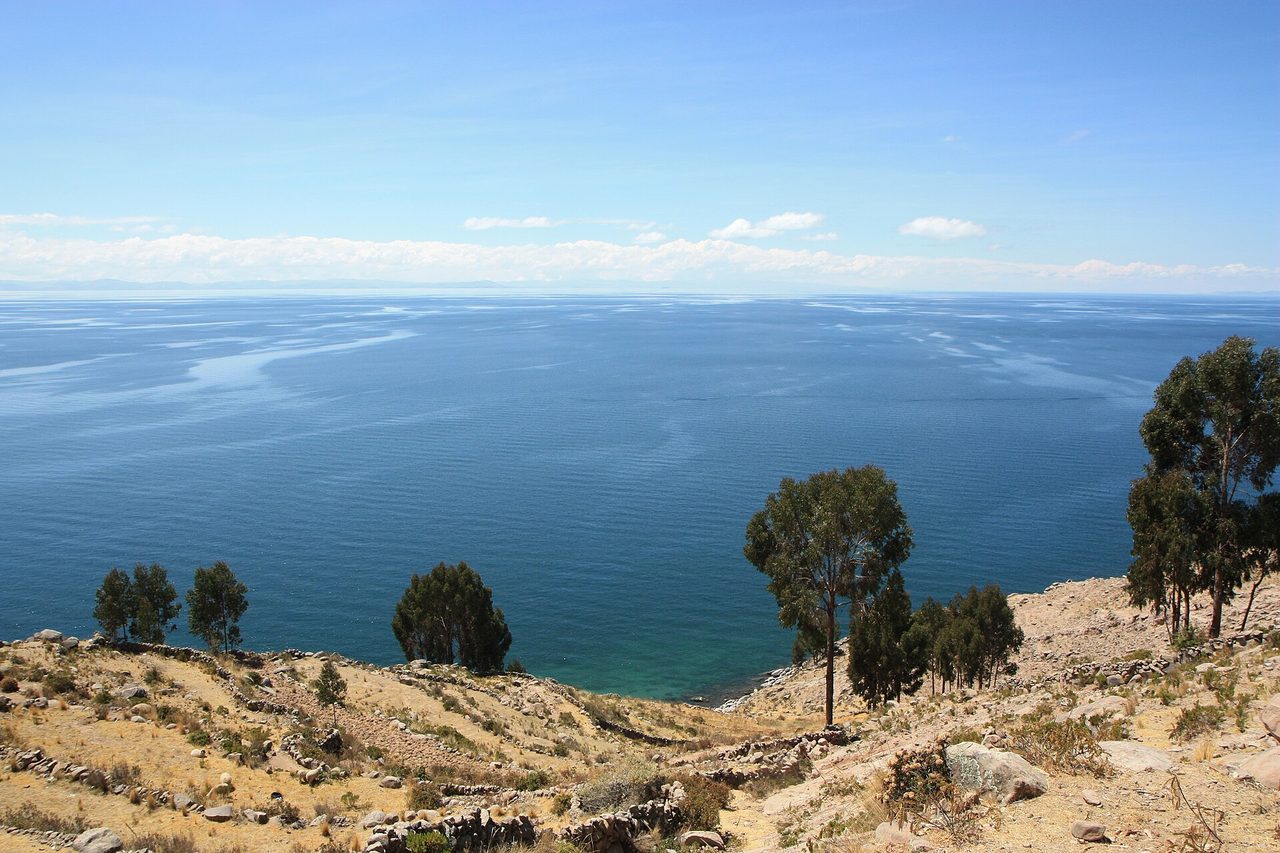 Dry terraced slopes of Taquile Island dropping to the deep blue open water of Lake Titicaca