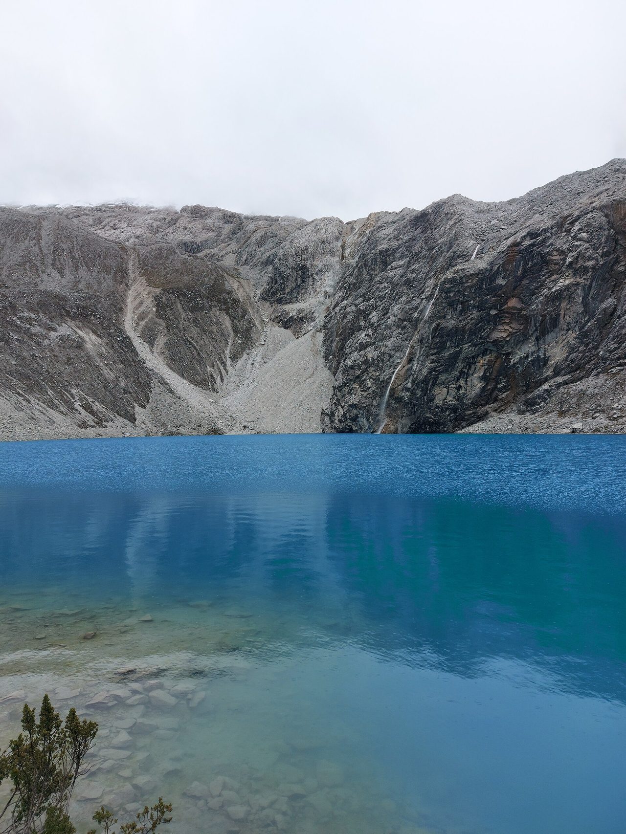 Deep blue glacial lake below grey rock walls in the Cordillera Blanca above Huaraz