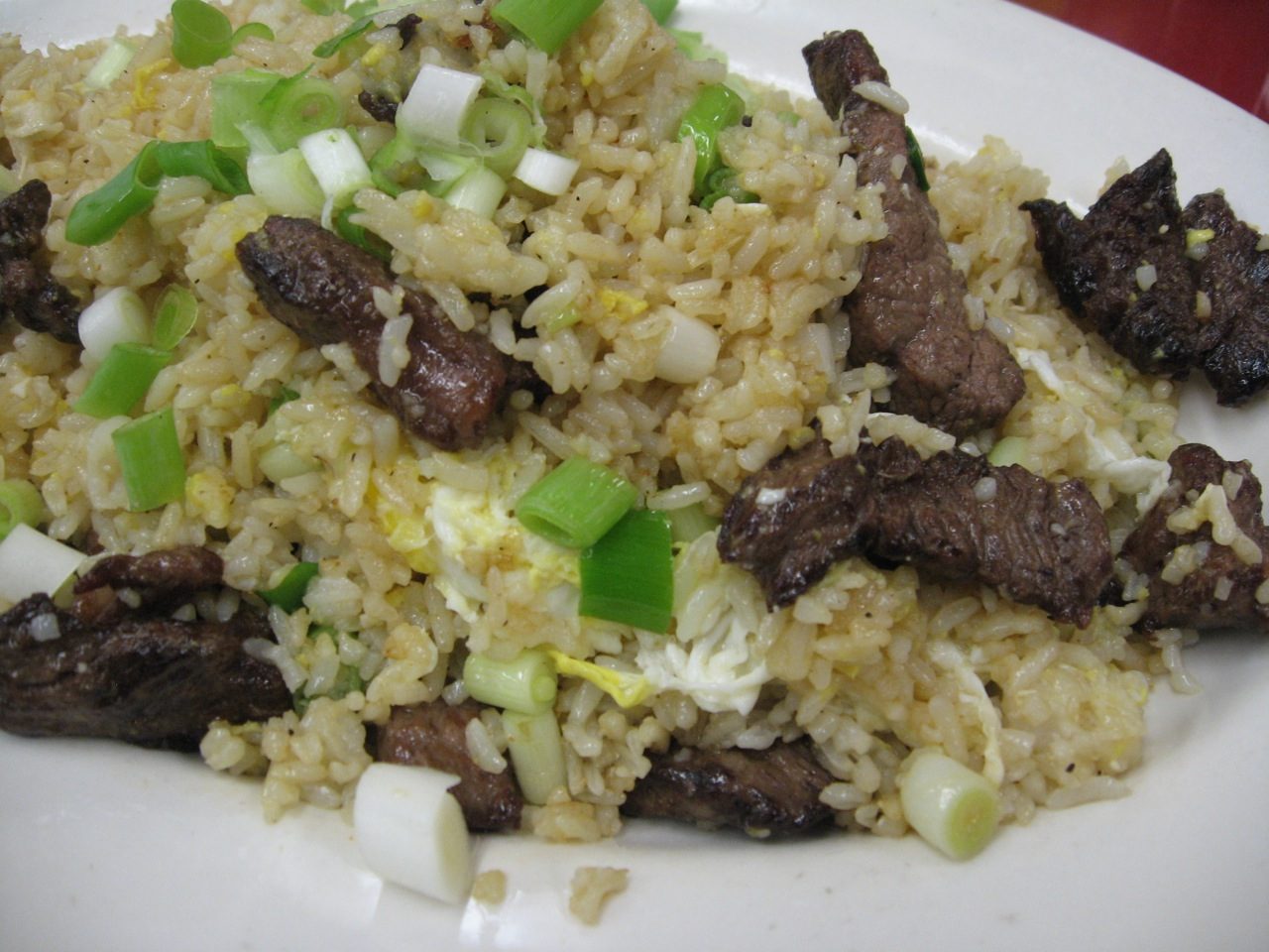 A plate of arroz chaufa, Peruvian-Chinese fried rice with strips of beef, egg and chopped spring onion