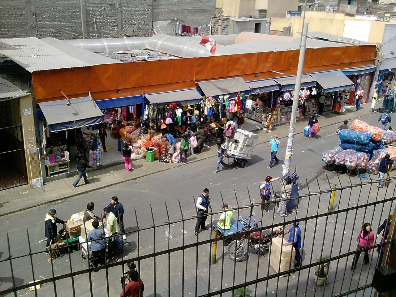 Market stalls, shoppers and porters with handcarts on a busy trading street beside Lima's Barrio Chino