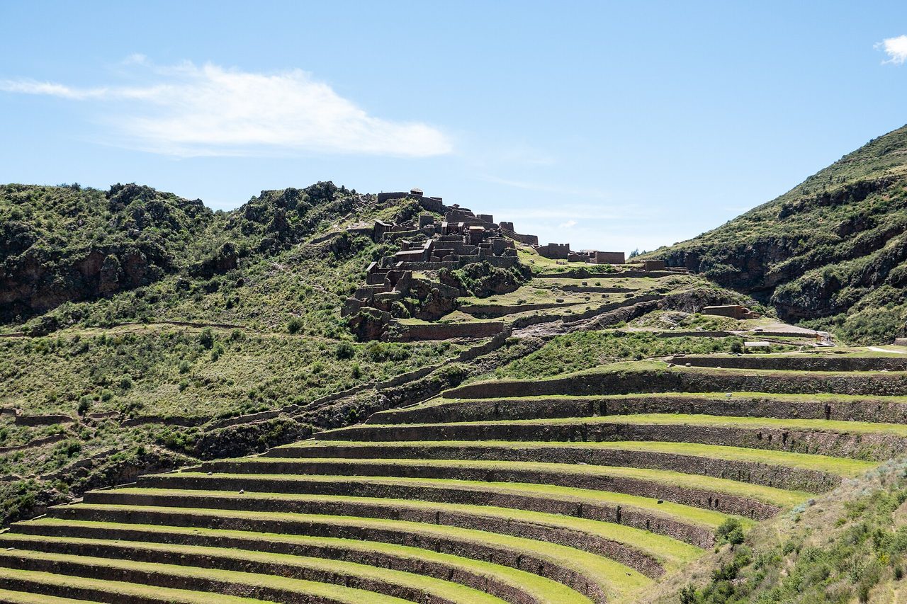 The curved green agricultural terraces of Pisac in the Sacred Valley climbing towards the Inca ruins on the ridge