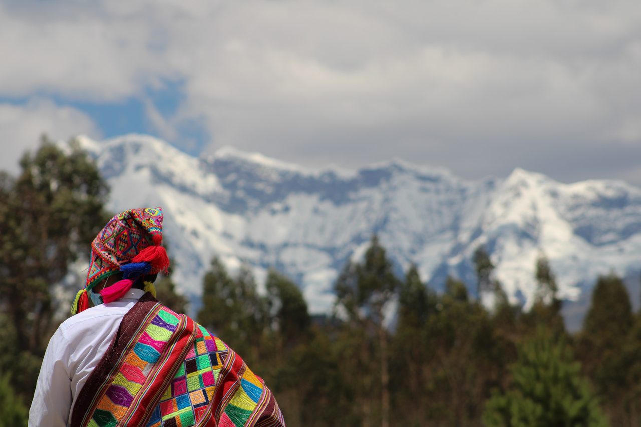 A man in a woven poncho and chullo looking towards the snow-covered Ausangate massif near Ocongate