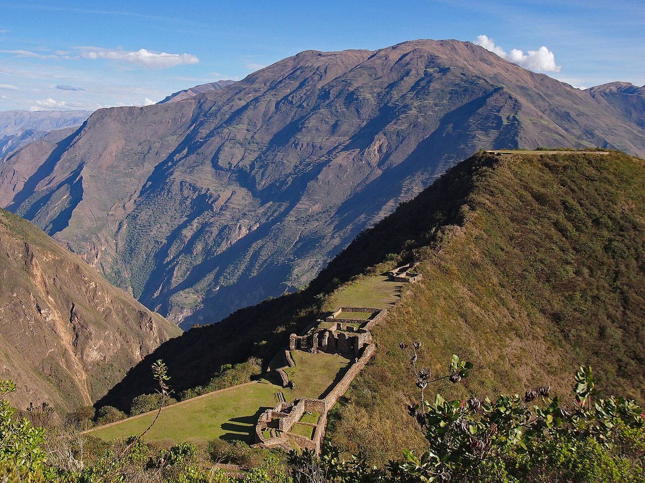 The lower plaza and truncated hilltop platform of Choquequirao on a green ridge, with the Apurimac canyon dropping away to the left