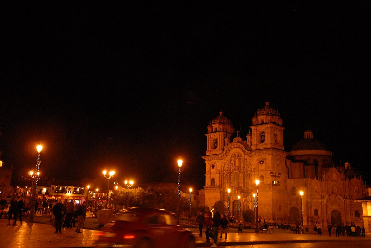 The Plaza de Armas in Cusco after dark, the Compania de Jesus church floodlit above the arcades