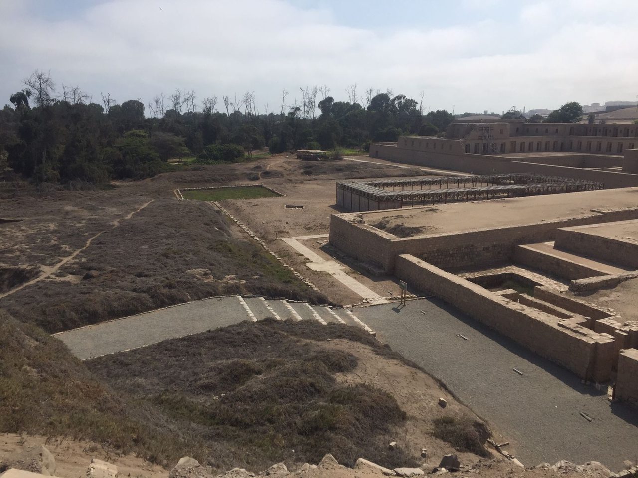 Restored Inca compound and adobe walls at the Pachacamac archaeological sanctuary, with the green Lurin valley behind