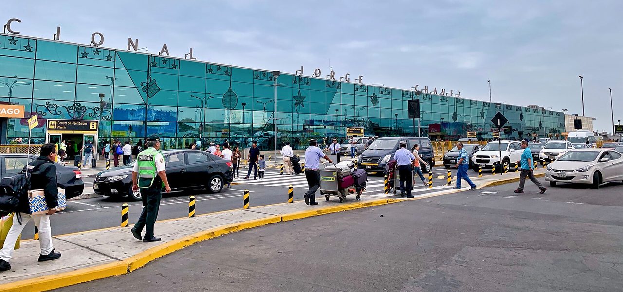 Passengers, porters and taxis on the kerbside outside the glass-fronted Jorge Chavez International Airport terminal in Lima