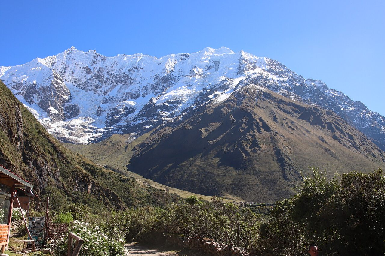 The dirt track on the valley floor near the Soraypampa trailhead, passing a small roadside restaurant, with the glaciated massif ahead