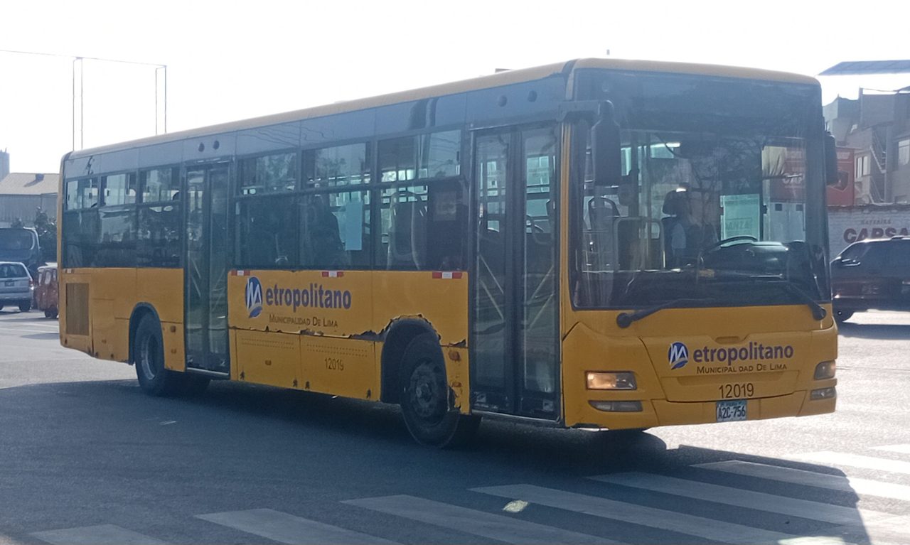 A yellow Metropolitano feeder bus marked Municipalidad de Lima crossing an intersection in Lima