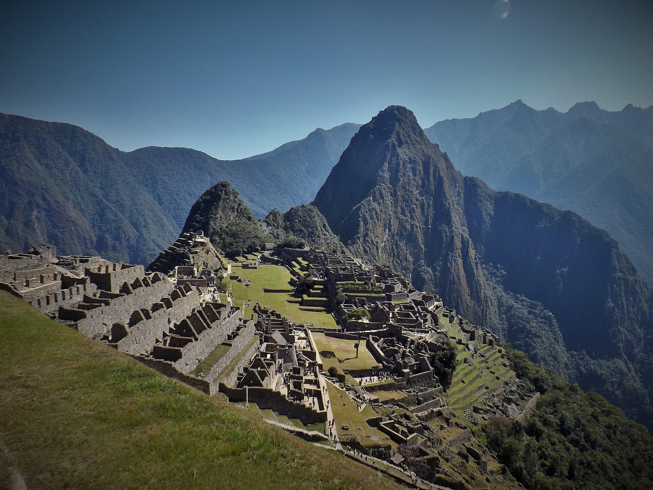 Machu Picchu's urban sector seen from the upper terraces, with visitors small on the paths below