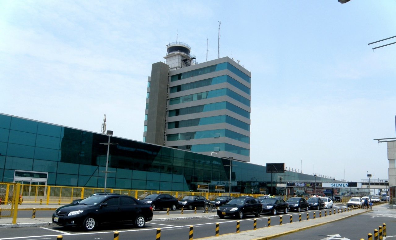 The Jorge Chavez control tower above a terminal frontage with a line of black airport taxis waiting at the kerb