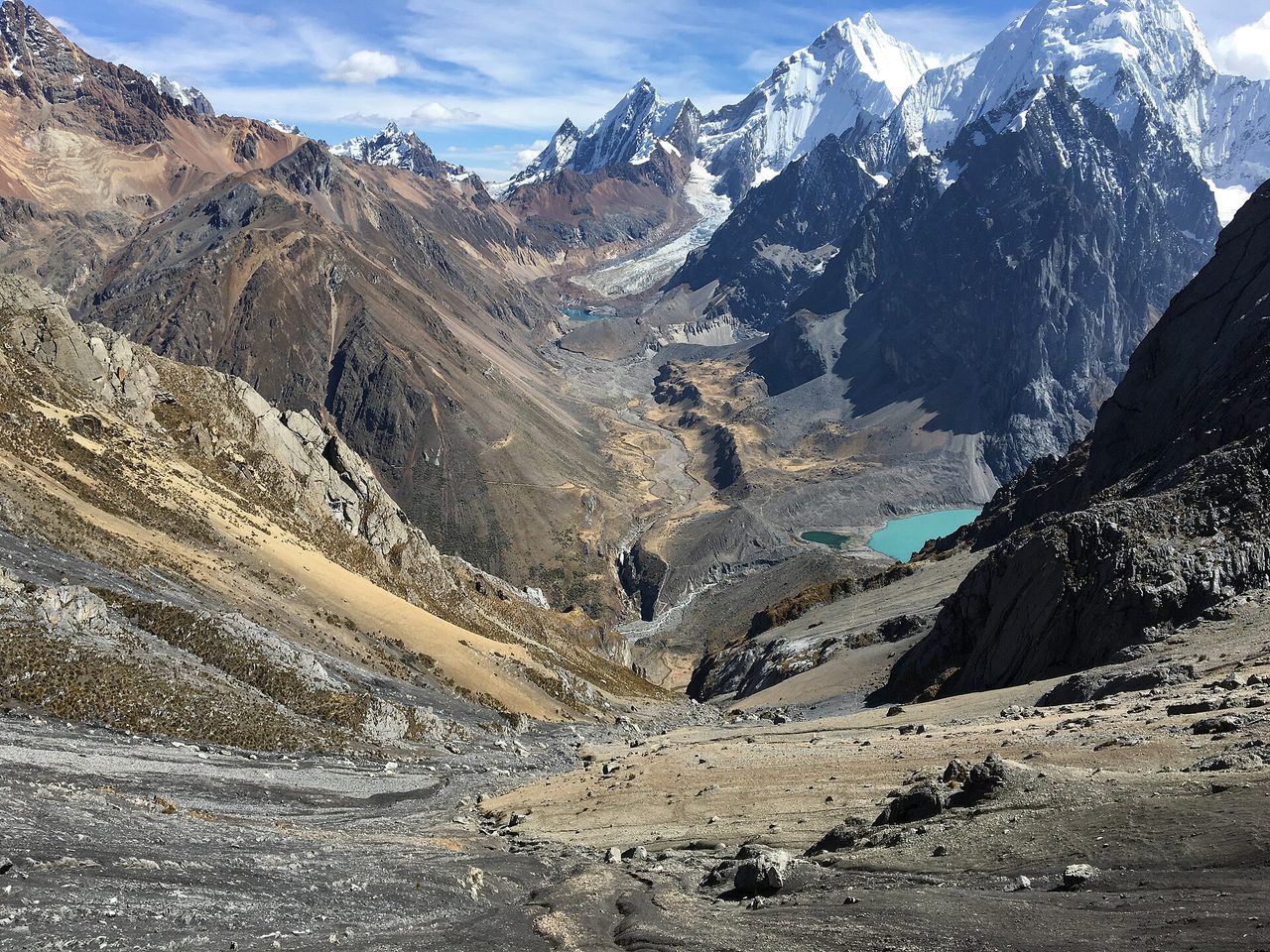 Snow and ice peaks of the Cordillera Huayhuash above a turquoise glacial lake and a wide moraine valley in Ancash, Peru