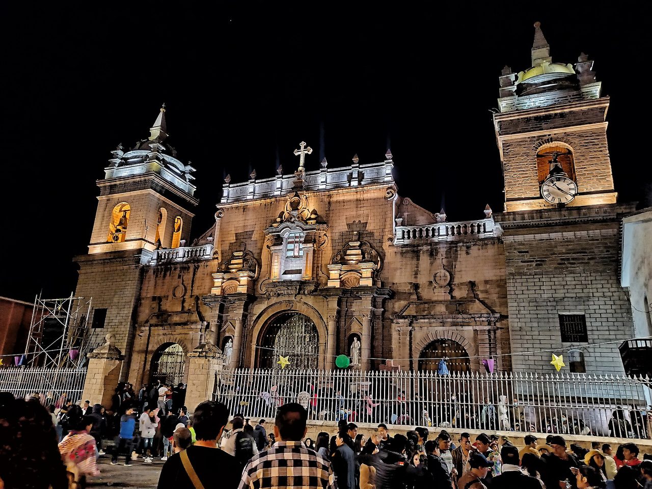 The floodlit twin-towered cathedral of Huamanga in Ayacucho at night, with crowds filling the plaza in front of it during Semana Santa