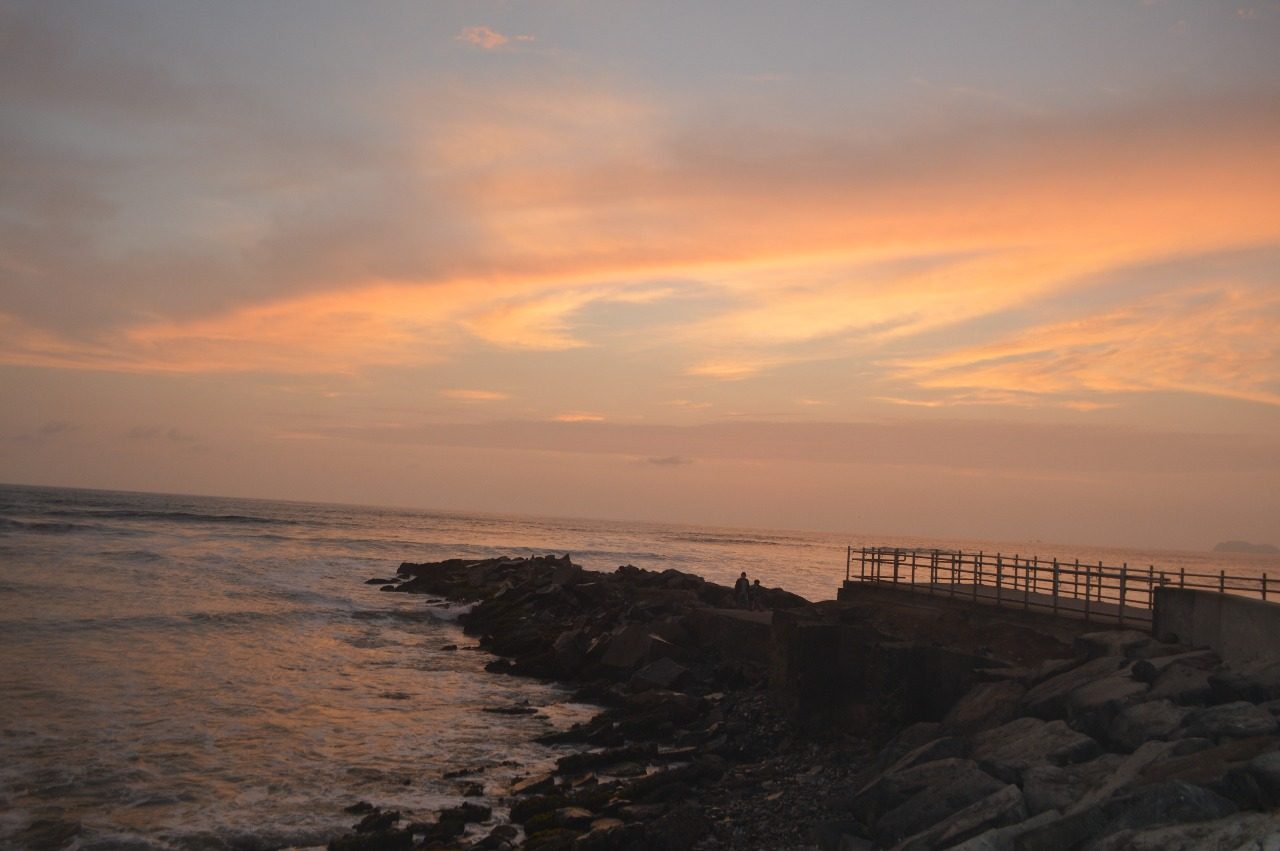 Waves breaking against the rocky Costa Verde shoreline below Lima in fading evening light