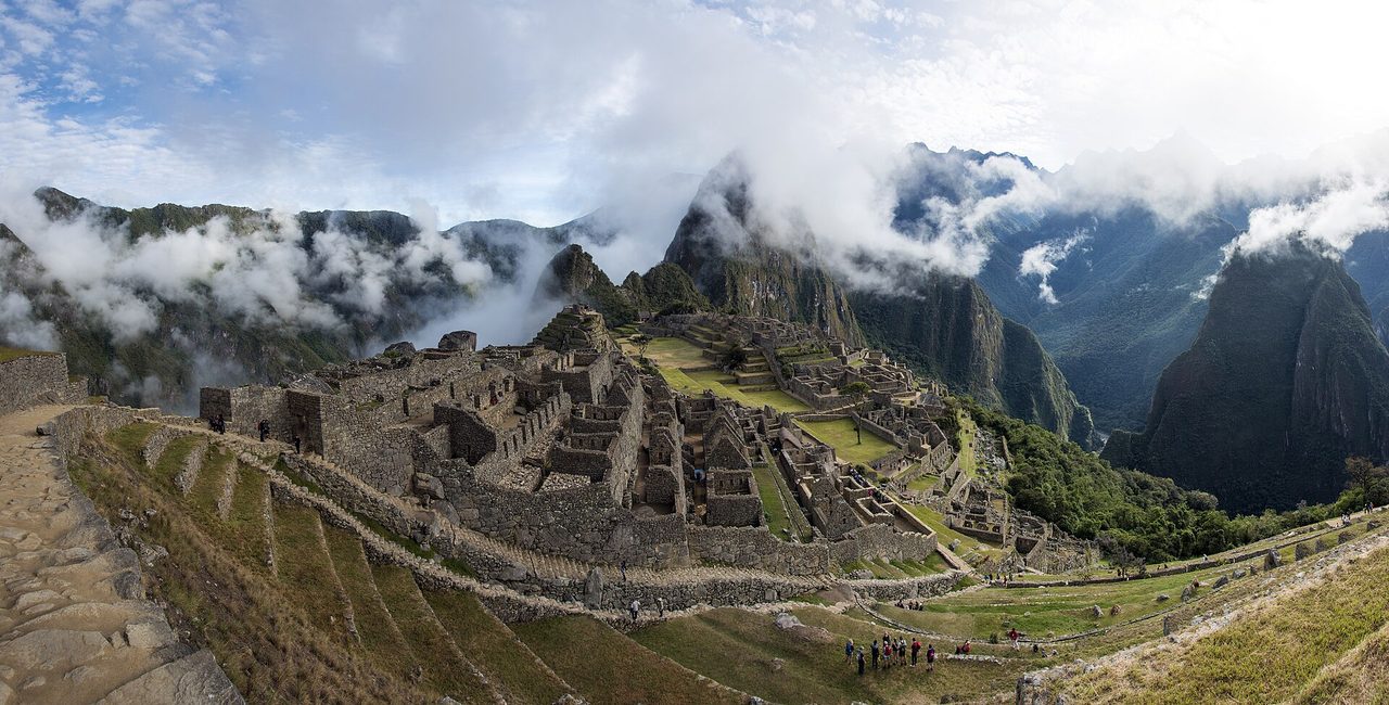 Cloud breaking over the terraces and stone buildings of Machu Picchu with Huayna Picchu behind
