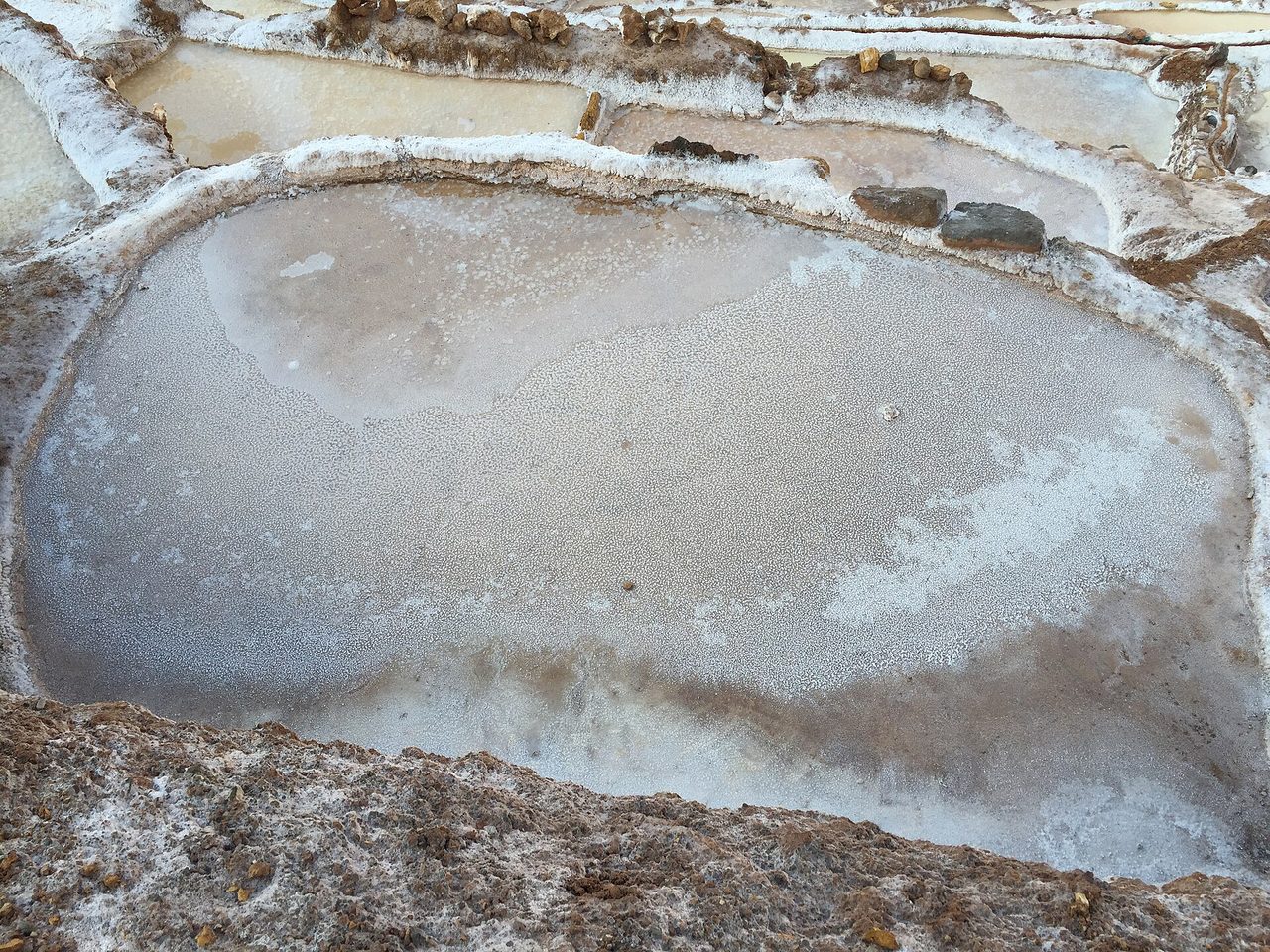 A single salt evaporation pond crusted with white salt at the Maras salt pans near Cusco