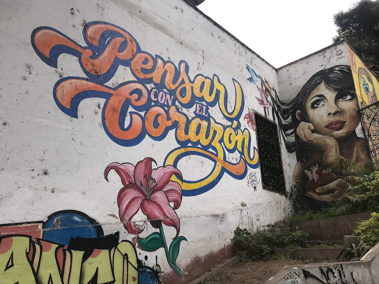 Painted murals on a wall in the Barranco district of Lima under a flat white overcast sky