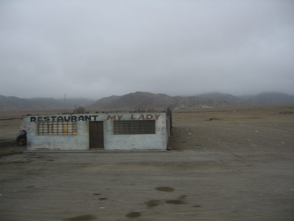 Thick grey coastal fog hanging over the bare desert hills and a lone roadside restaurant on the Peruvian coast between Lima and Trujillo