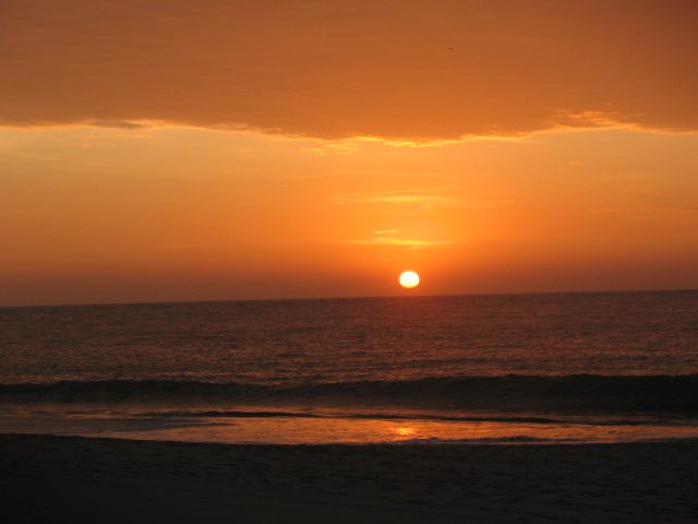 Sunset over calm surf on the wide sandy beach at Punta Sal on Peru's warm north coast