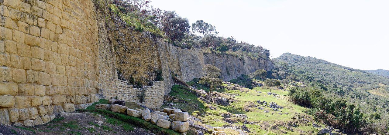 The high limestone perimeter wall of Kuelap curving along a green ridge in northern Peru
