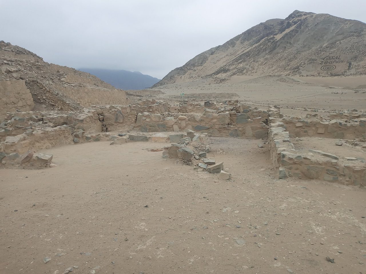 Low stone walls of the ancient city of Caral on a dry desert terrace in the Supe valley