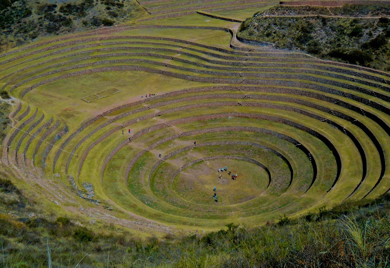 The concentric circular agricultural terraces of Moray in the Sacred Valley, with people walking on the lowest ring