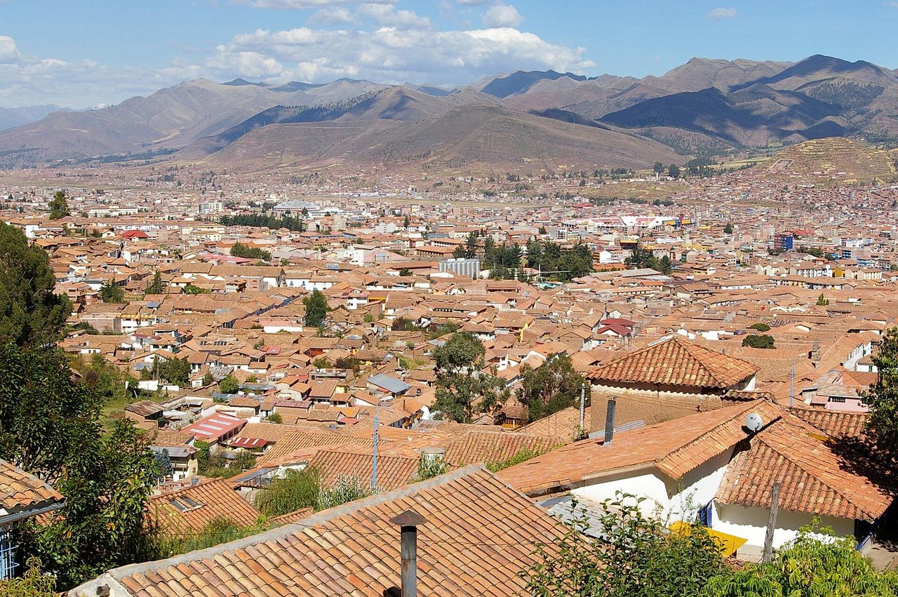 Red-tiled rooftops of Cusco spreading across the valley floor, seen looking down from the hillside neighbourhoods above the historic centre
