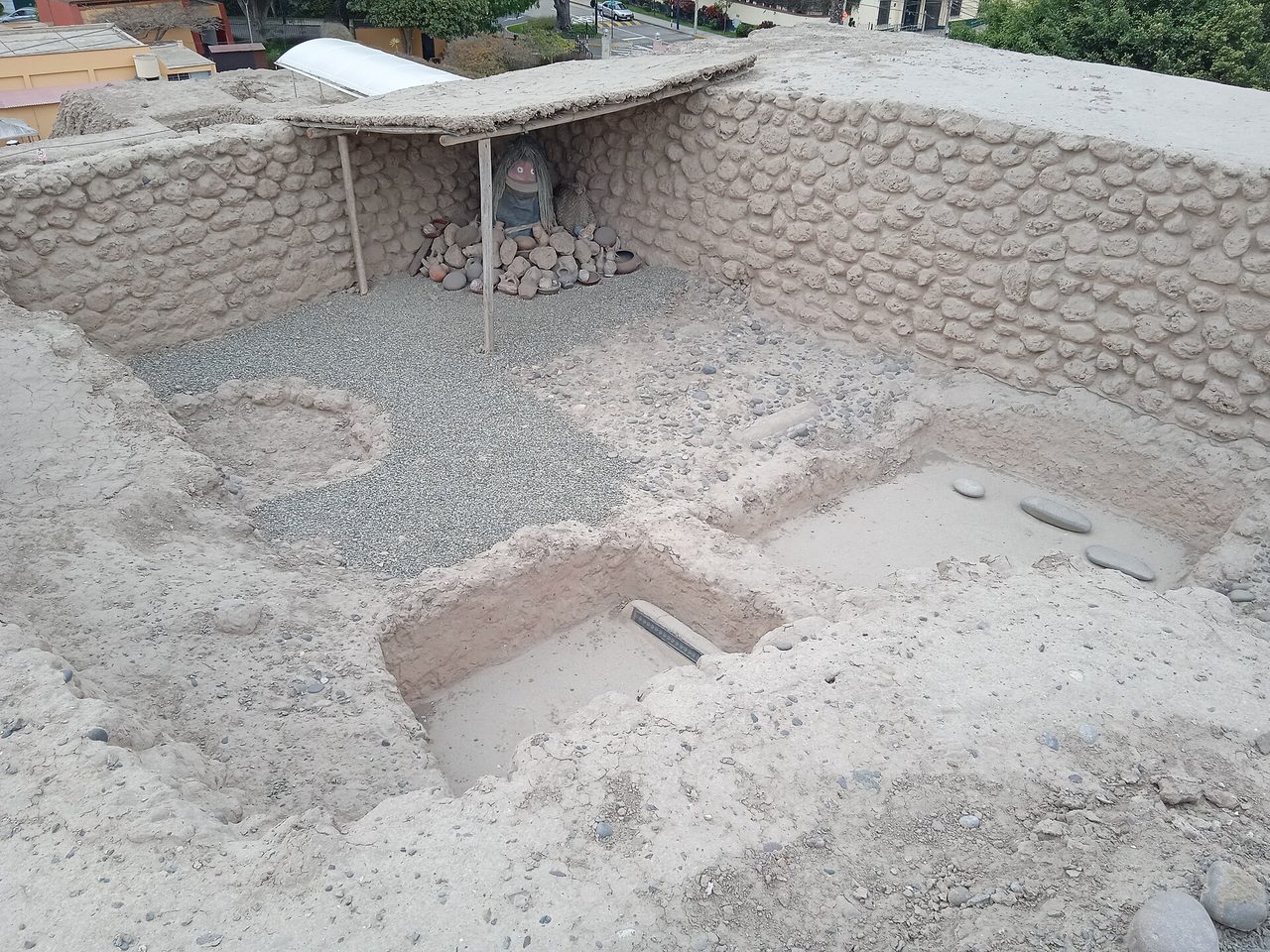 Excavated adobe walls and a reconstructed burial with pottery at Huaca Huallamarca in San Isidro