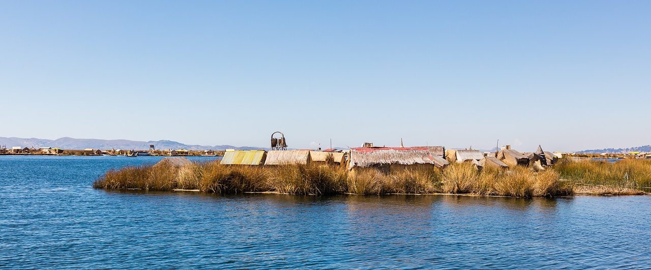 Thatched reed huts on one of the Uros floating islands on Lake Titicaca under a clear altiplano sky