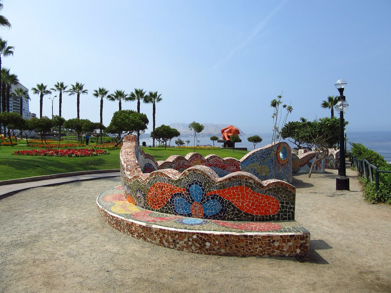 Mosaic benches at the Parque del Amor on the Miraflores clifftop in Lima, with palms and the Pacific behind
