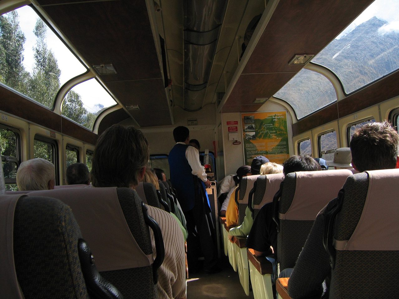Interior of a panoramic Vistadome carriage with roof windows, passengers and an attendant in the aisle