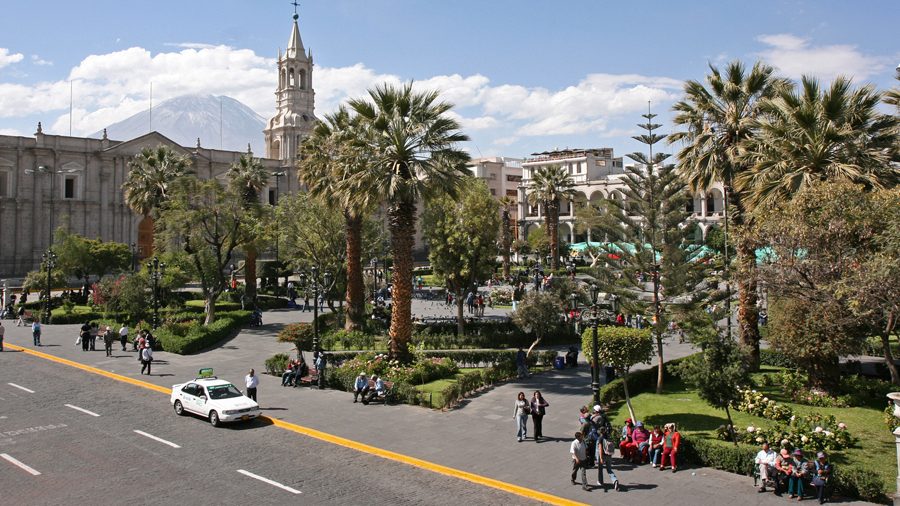 The palm-filled Plaza de Armas in Arequipa with the cathedral bell tower and El Misti volcano behind it