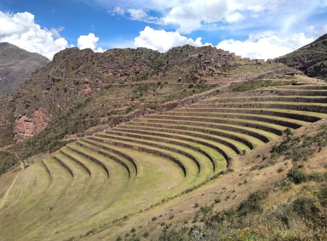 Curved Inca agricultural terraces at Pisac with the citadel buildings on the ridge crest above them