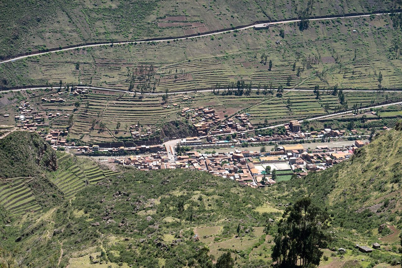Aerial view of Pisac town beside the Urubamba river with terraced hillsides behind it