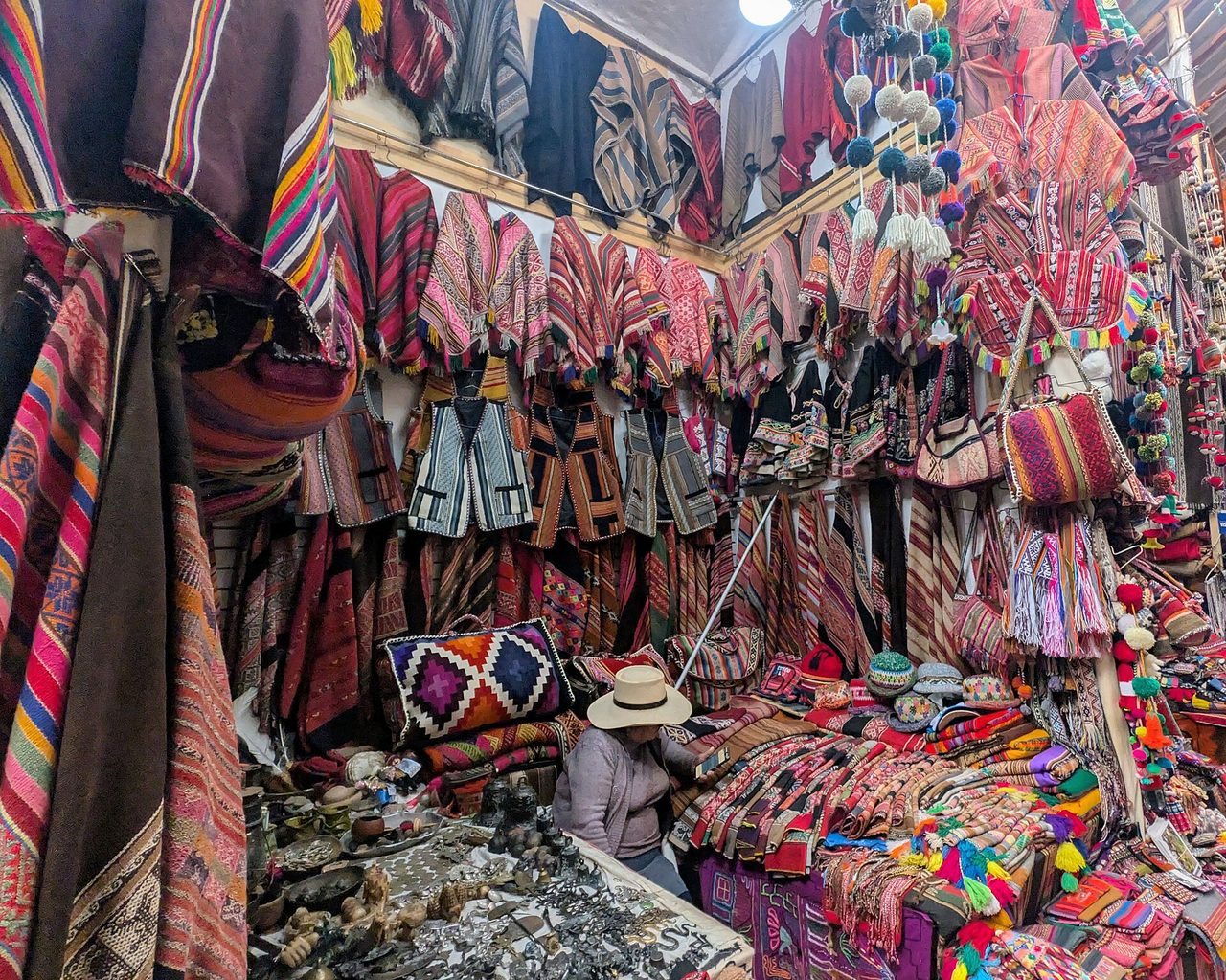 A stall hung with ponchos, blankets and woven bags at the Pisac artisan market
